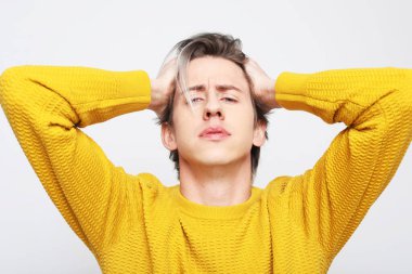 Sarı kazak giyen genç adam korkmuş ve şaşkınlık dolu bir ifade, korku ve heyecanlı bir yüz ifadesiyle şok olmuştu. Yaşam tarzı ve insan kavramı.