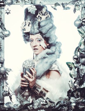 Parti, noel ve halk konsepti: Gümüş sanatsal makyajlı, Noel süslemeleri ile süslenmiş gümüş çerçevede poz veren yaratıcı görünümlü genç kadın. Kış Portresi.