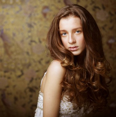 Moda, güzellik ve insan konsepti: Kameraya bakan uzun dalgalı saçlı çekici genç kadın