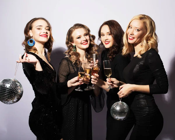 Four Party women in black dress with disco balls and wine over white background