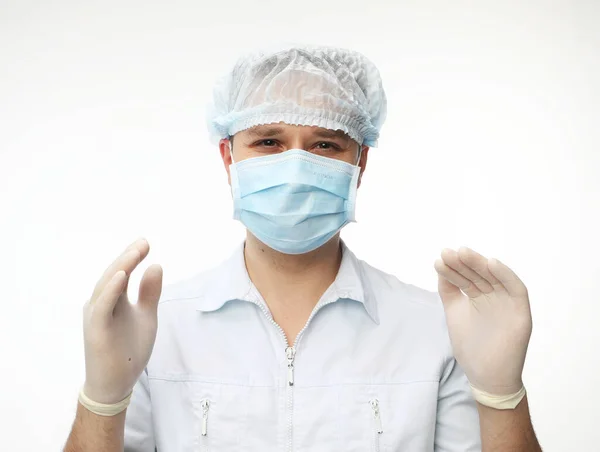 a male doctor in gloves, a medical cap and a mask holds his hands up, getting ready for the operation over white background