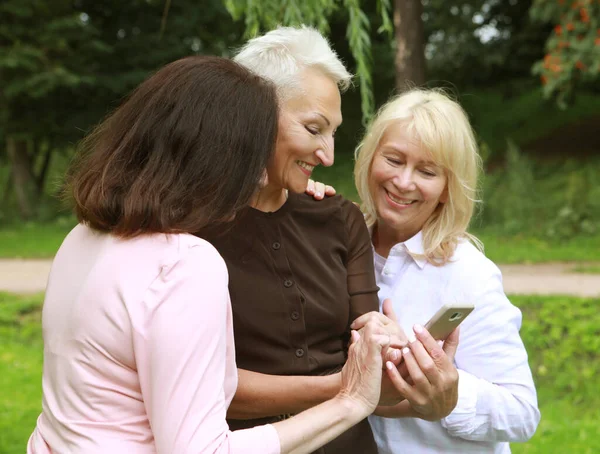 Three Elderly Women Smiling Looking Photos Screen Phones Park Summer — Stock Photo, Image