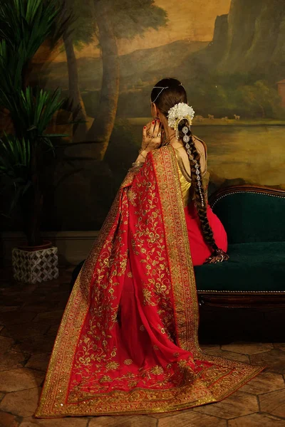 Urocza Młoda Kobieta Siedzi Kanapie Tradycyjne Indyjskie Sari Ślubne Biżuteria — Zdjęcie stockowe