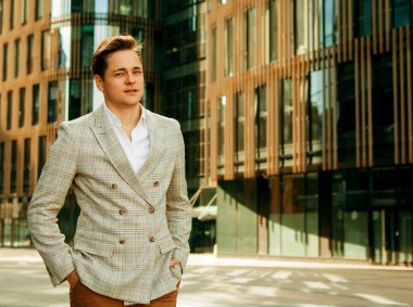 İş dünyası, insanlar ve yaşam tarzı konsepti: Yakışıklı bir iş adamının portresi, yaz günü, modern iş merkezinin yakınında açık hava