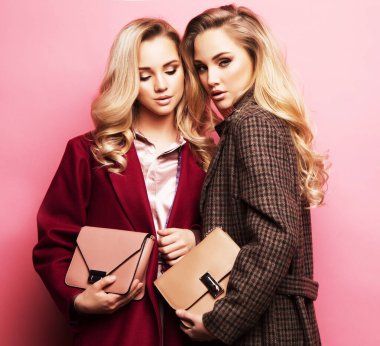 Poz güzel elbiseler, ceket, çanta iki tatlı genç sarışın kadın. Kız kardeş, İkizler. Bahar moda fotoğraf.