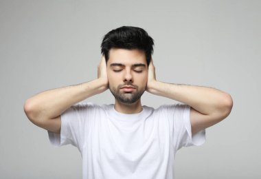 adam tutun ellerde tapınaklar kulaklar, vurguladı adam kavramı, baş ağrısı, depresyon, ağrı, Beyaz tişört, beyaz izole kapalı gözler giymek.