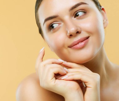 Beautiful Young Woman with Clean Fresh Skin look away. Portrait over beige background, close up. Cosmetology , beauty and spa concept.