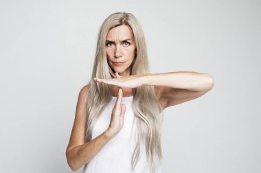 Jest, içki yasağı ve yaşlı insan konsepti: Gri arkaplan üzerinde mola veren uzun gri saçlı yaşlı kadın.