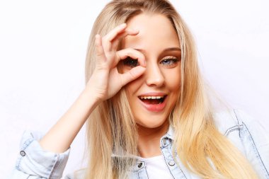 Yaşam tarzı ve insan konsepti - Mutlu heyecanlı genç kadın beyaz arka planda parmaklarından oluşan delikten bakıyor, yakın plan