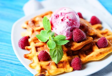 Taze böğürtlenli Belçika waffle 'ları ve mavi ahşap arka planda dondurma.