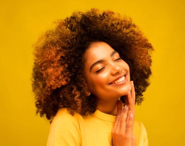 Hoş, koyu tenli, çekici, Afro saçlı genç bir manken gözlerini kapatıyor, favori müzikten hoşlanıyor, yalnız zaman geçiriyor, geniş bir gülüşü var. İnsanlar, eğlence ve mutluluk konsepti.