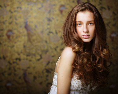 Moda, güzellik ve insan konsepti: Kameraya bakan uzun dalgalı saçlı çekici genç kadın