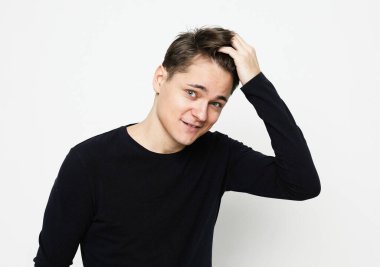 Siyah süveter giyen genç adamın beyaz arka planda kameraya baktığı belden yukarı pozlar.