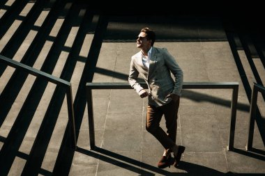 İş ve insan kavramı: Genç iş adamı merdivenlerden çıkıyor, yaz zamanı.