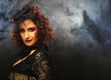 Siyah şapkalı, duvağı ve lüks elbisesi olan orta yaşlı zarif bir kadın. Eski tarz. Duman arkaplanı üzerinde portre.