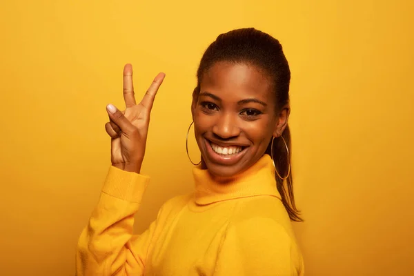 Young beautiful African American afro woman wearing yellow casual sweater showing and pointing up with fingers number two while smiling confident and happy.