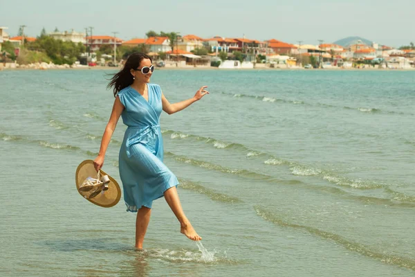 Młoda Brunetka Niebieskiej Sukience Chodząca Boso Plaży Wymachująca Nogami Wodzie — Zdjęcie stockowe