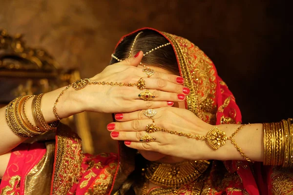 Young hindu woman model kundan jewelry. Traditional Indian costume yellow saree. Indian or Muslim woman covers her face.