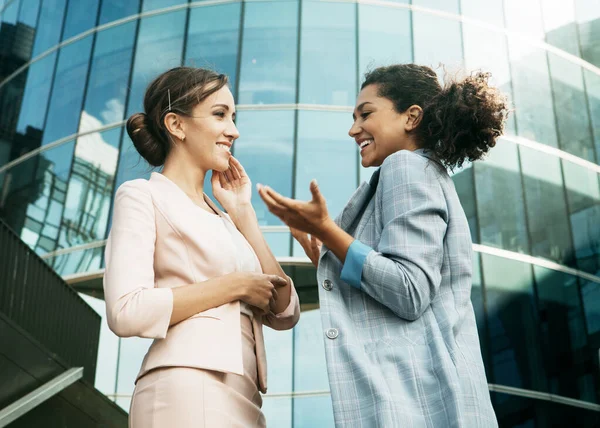Lifestyle, business and people concept: Two business women having a casual meeting or discussion near a modern office