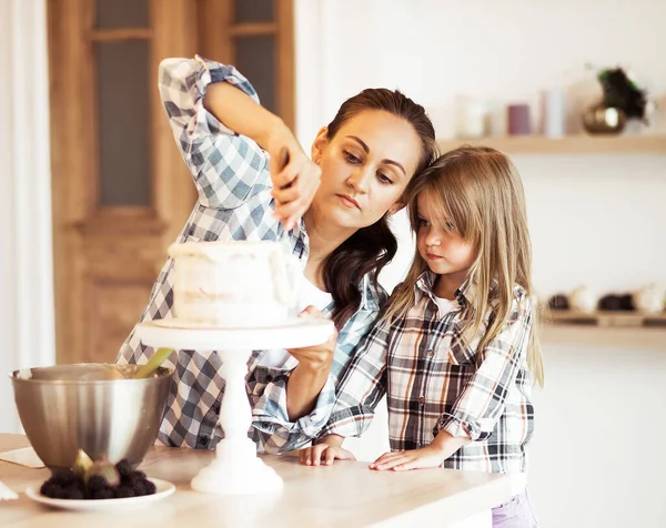 家族の創造性 子供たちとの共同活動 若い母親と彼女の4歳の娘がクリームでケーキを飾る — ストック写真