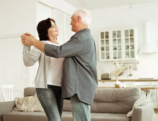 快乐快乐活泼的老夫妇在厨房里跳舞 快乐快乐的退休大丈夫牵着成熟的中年妻子的手在家里享受着悠闲的退休生活 — 图库照片
