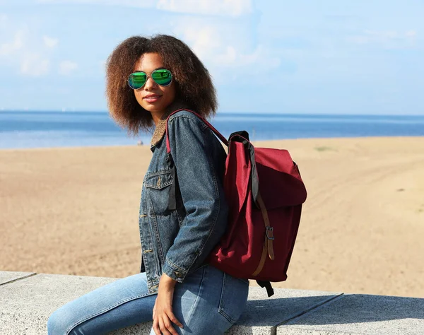 Beautiful Young African Woman Denim Jacket Sunglasses Backpack Resting While — Zdjęcie stockowe