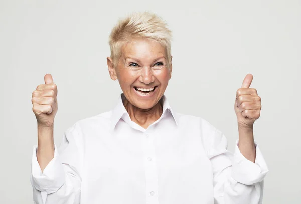 Portrait Cheerful Mature Woman White Shirt Showing Thumbs Gesture Grey — Stock Photo, Image