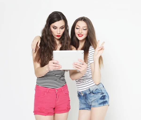 テクノロジーと友情と人々の概念 グレーの背景にタブレットPcを持つ2人の笑顔の若い女性 — ストック写真