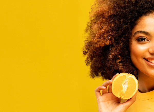 lifestyle, food, diet and people concept: He holds bright ripe citrus, oranges in his hands. Portrait of a female model of Afro appearance. Black hair is curly.
