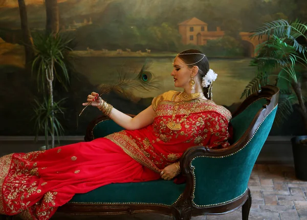 Charming Young Woman Holding Peacock Feather While Sitting Sofa Traditional — Foto de Stock