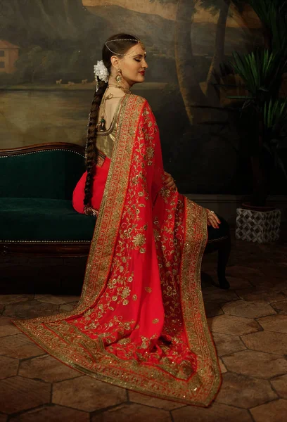 迷人的年轻女子正坐在沙发上 印度传统婚纱和珠宝 — 图库照片