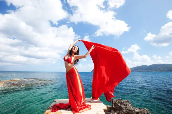 年轻的黑发女人 红色的裙子和像翅膀一样的面料 近海地区的女模 夏季时间 — 图库照片