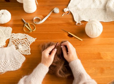 Yün örgü ören kadın ellerinin yakın çekimi. Kahverengi atkı. Üst Manzara. Serbest çalışıyorum. Hobi.