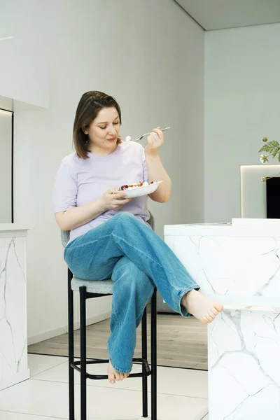 漂亮的胖女人坐在厨房里吃沙拉 生活方式概念 — 图库照片
