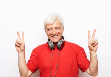 Elderly man with headphones over white background. Handsome man show victory sign. Win.