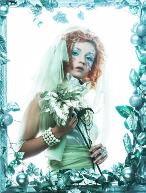 Parti, noel ve halk konsepti: Noel karnavalı için kostüm giymiş güzel kızıl bir kadın Noel süslemeleri çerçevesinde poz veriyor ve elinde bir çiçek tutuyor. Kış stili, Kar Kraliçesi.