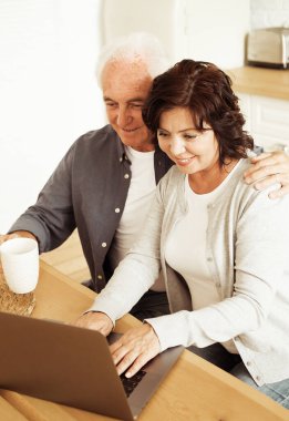Elderly husband and wife using digital tablet at home, kitchen room, happy family