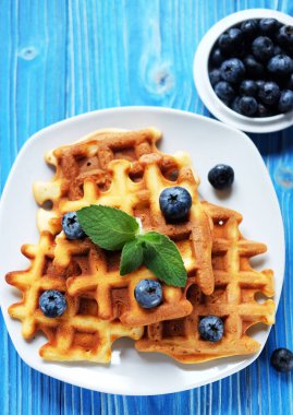 Good morning. Waffles with blueberries for breakfast over blue wooden table.