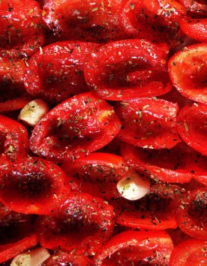 Yemek arkaplanı. Domatesler fırın tepsisine konmuş, pişirmeye hazır. Sarımsaklı güneşte kurutulmuş domates. Kapat..
