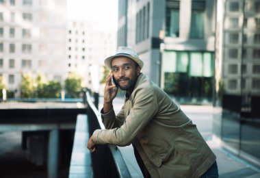 Young handsome Afro American man smiling and talking on cell phone on the street. Lifestyle concept.