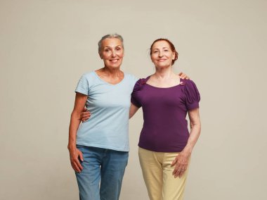 Two pretty elderly women friends on grey background. Lifestyle concept.