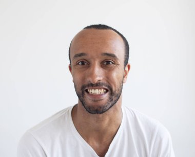 A young unshaven smiling man on a light gray background. African American. Close-up portrait.