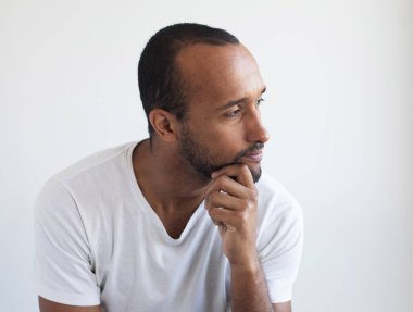 A young unshaven man on a light gray background. African American. Close-up portrait.