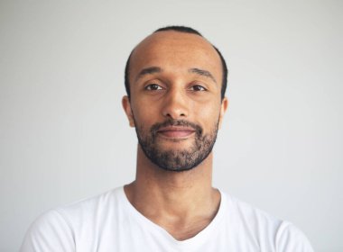 A young unshaven smiling man on a light gray background. African American. Close-up portrait.
