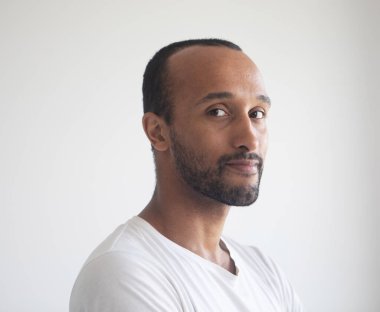 A young unshaven smiling man on a light gray background. African American. Close-up portrait.