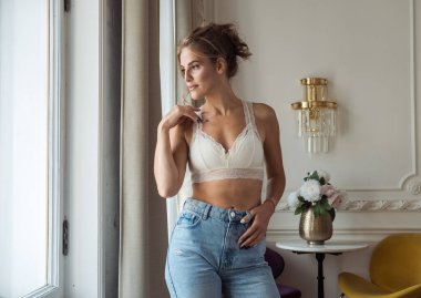 Kotlu ve dantelli bluzlu çekici sarışın kadın oturma odasında duruyor, yaşam tarzı konsepti.