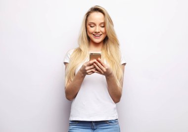 Young beautiful blond smiling surprised woman with smart phone over white background