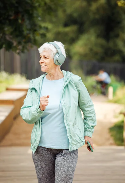 Elderly Woman Short Haircut Dressed Sportswear Jogging Park While Listening — Fotografia de Stock