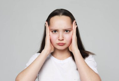 Portrait of sad woman having toothache and touching cheek over grey background