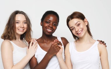 Portrait of charming multiracial female friends over light grey background. Lifestyle, friendship and people concept.
